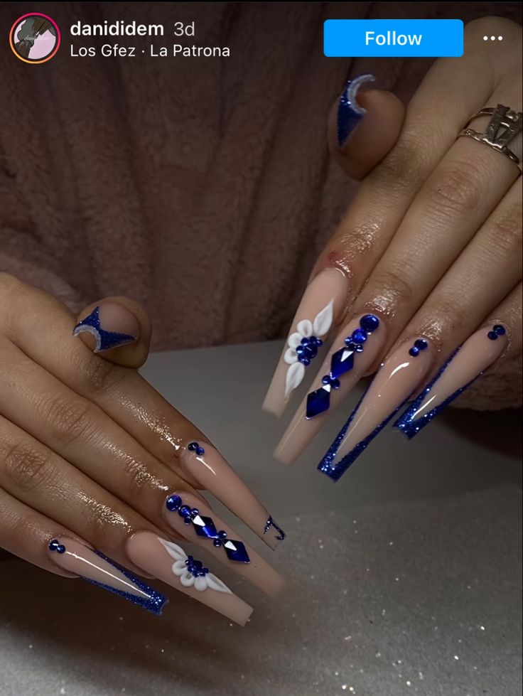 Elegant Nude and Vibrant Blue Nail Design with Floral Accents and Gems.