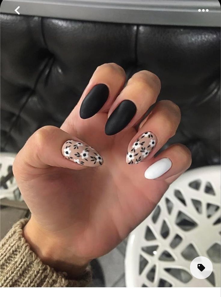 Chic Nail Design: Matte Black, White, and Playful Floral Patterns in Almond Shapes.