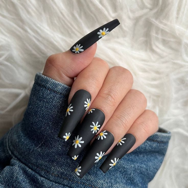 Striking Matte Black Nails with Whimsical White Daisies Combine Sophistication and Charm.