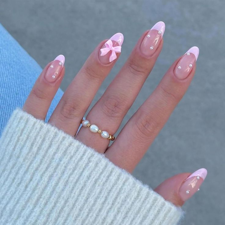 Sophisticated Pink and Nude Almond Nail Design with Pearls and Bow.