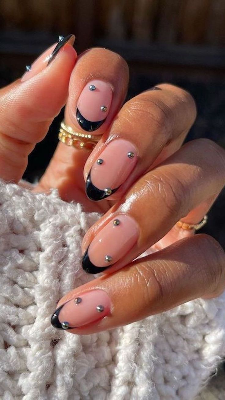 Sophisticated Nude Nail Design with Striking Black Tips and Rhinestone Accents.