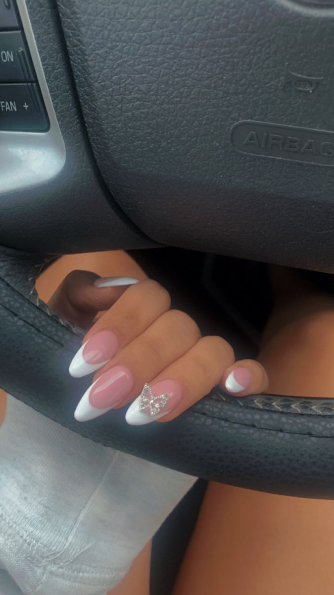 Chic Pink and White French Tip Nails with Jeweled Butterfly Embellishment.