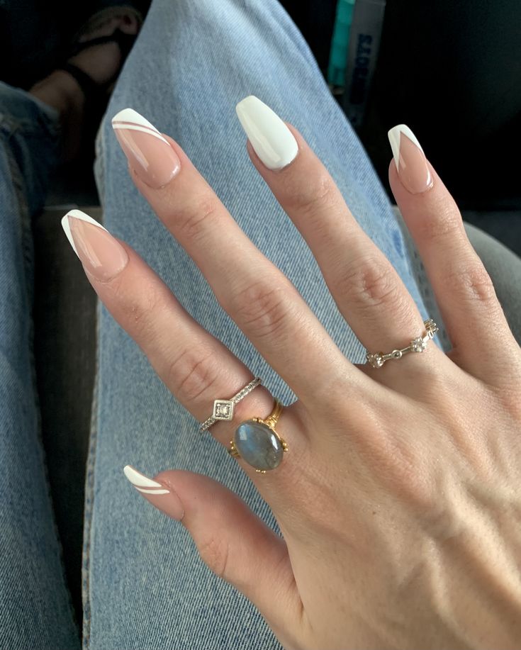 Chic Modern French Manicure: Elegant Beige and White Coffin Nails with Delicate Rings.