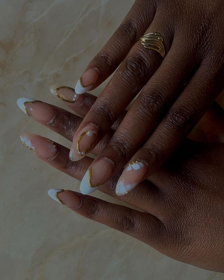 Sophisticated Nail Design Blending French Tips and Abstract Art with Gold Accents and Gemstone Embellishments.