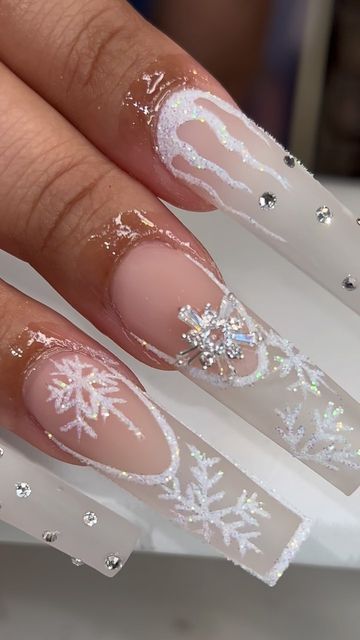 Elegant Winter Nail Design: Translucent Nails with Snowflake Patterns and Sparkling Rhinestones.