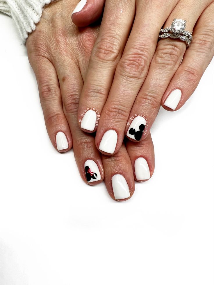 Chic White Nail Design with Whimsical Black and Red Character Accents.