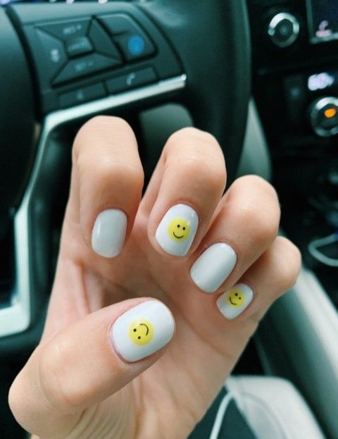 Cheerful Glossy White Nail Design Adorned with Playful Yellow Smiley Faces.