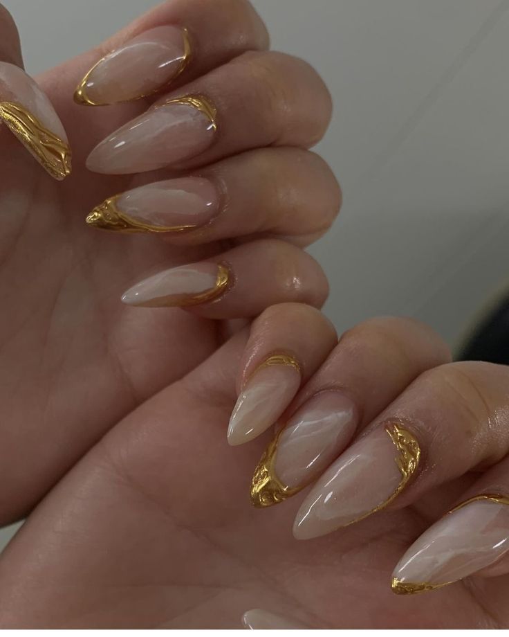 Sophisticated Almond-Shaped Nails: Nude Base with Glossy Finish and Gold Detailing.