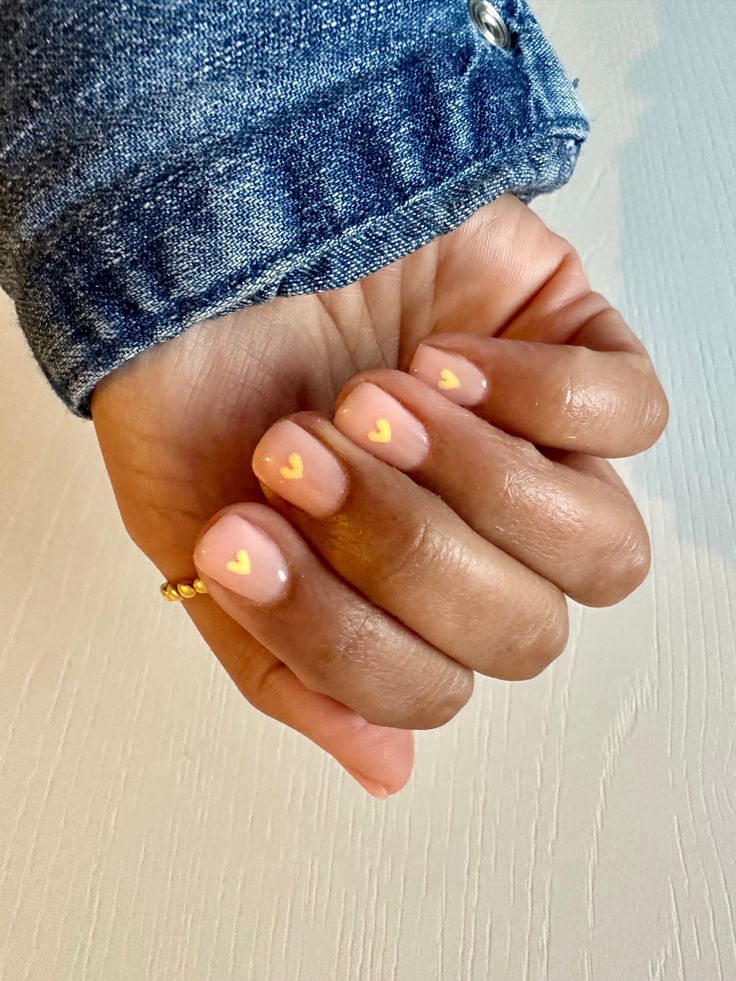 Charming Nude Nail Design with Delicate Yellow Heart Accents.