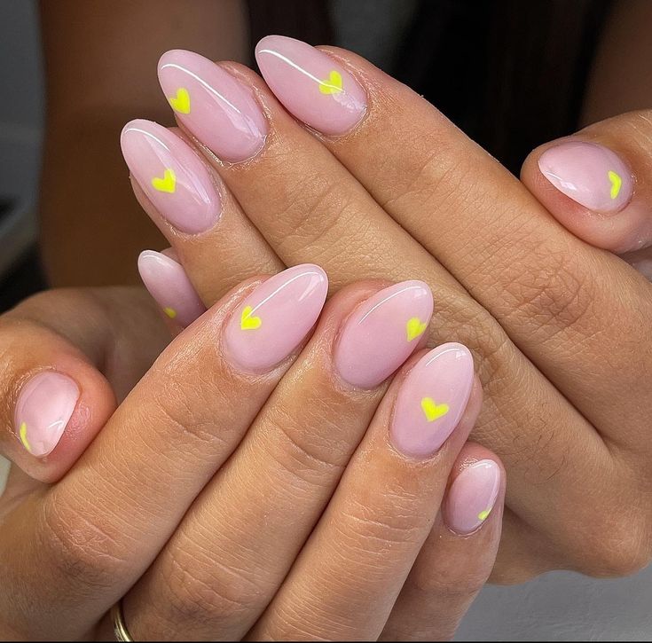 Charming Pastel Pink Nails with Whimsical Yellow Heart Designs.