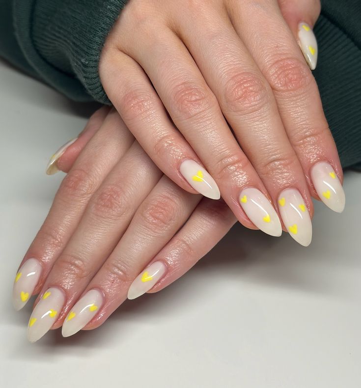 Elegant Almond-Shaped Manicure with Soft Nude Base and Cheerful Yellow Hearts