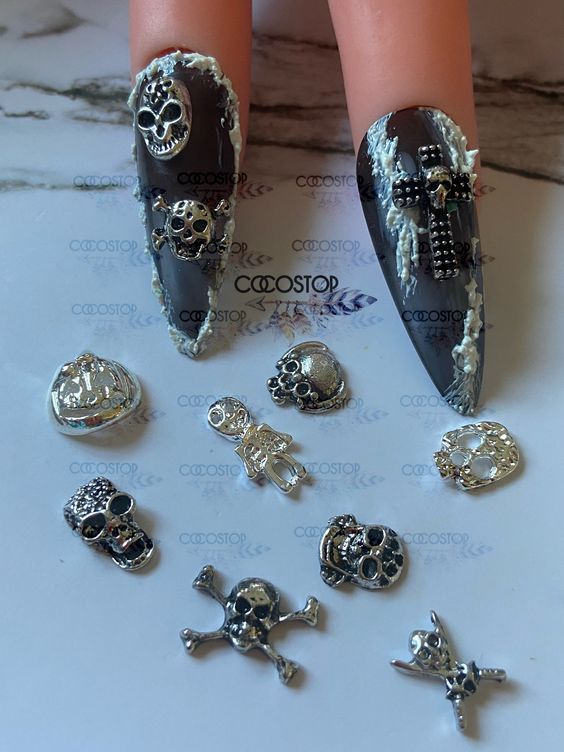 Gothic-Inspired Edgy Nail Design with Long, Glossy Black Pointed Nails and Skull Charms.