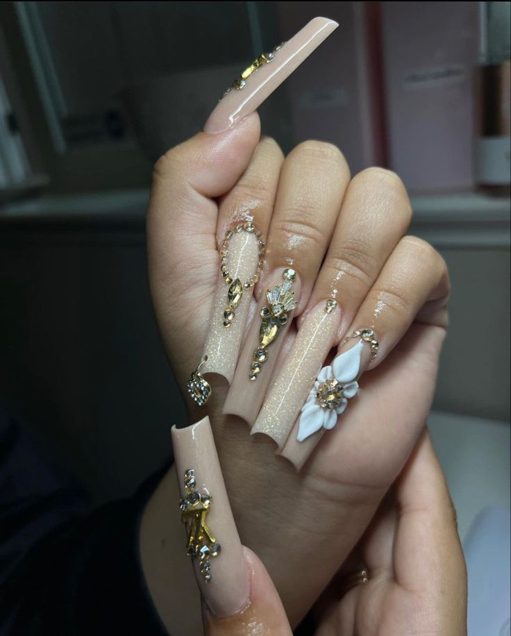 Luxurious Long Nude Stiletto Nails with Intricate Gold Accents, Flowers, and Gems.