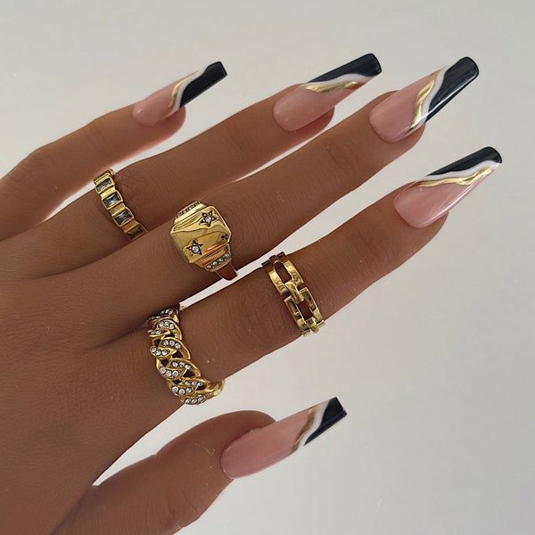 Chic Elongated Nail Design with Nude, Black, and Gold Accents for Modern Elegance.