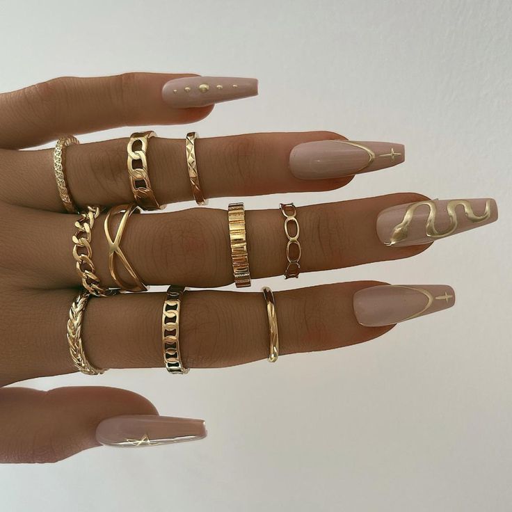 Sophisticated Almond-Shaped Nude Nails with Creative Gold Accents and Geometric Patterns.