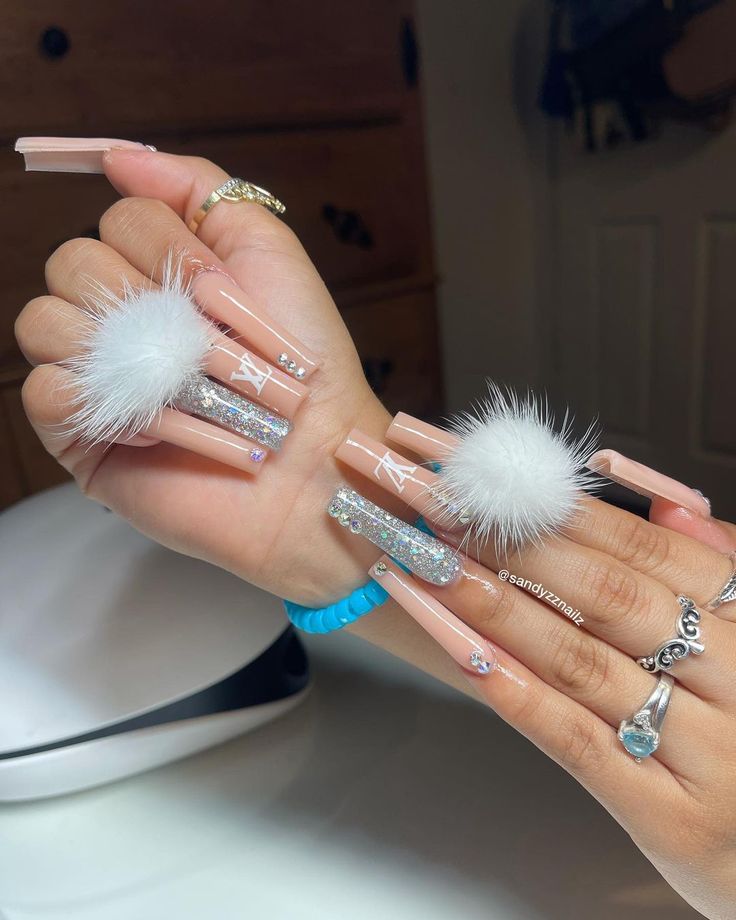 Bold and Chic Nail Art: Glittery Long Nails with Pom-Poms and Rhinestones.