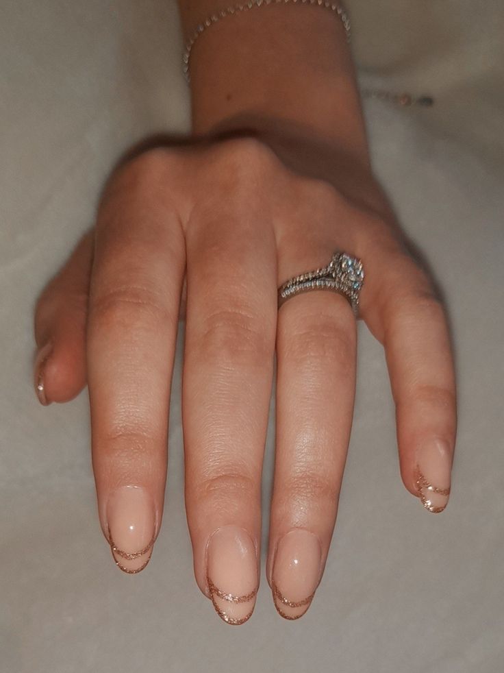 Sophisticated Nude Nail Design with Delicate Gold Accents and Subtle French Tips.