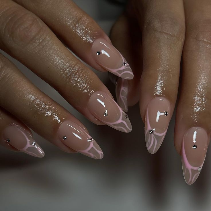 Elegant Stiletto Nails with Translucent Nude Base, Pink Swirls, and Dazzling Silver Studs.