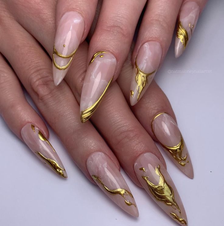 Luxurious Glossy Nude Stiletto Nails with Intricate Gold Designs.