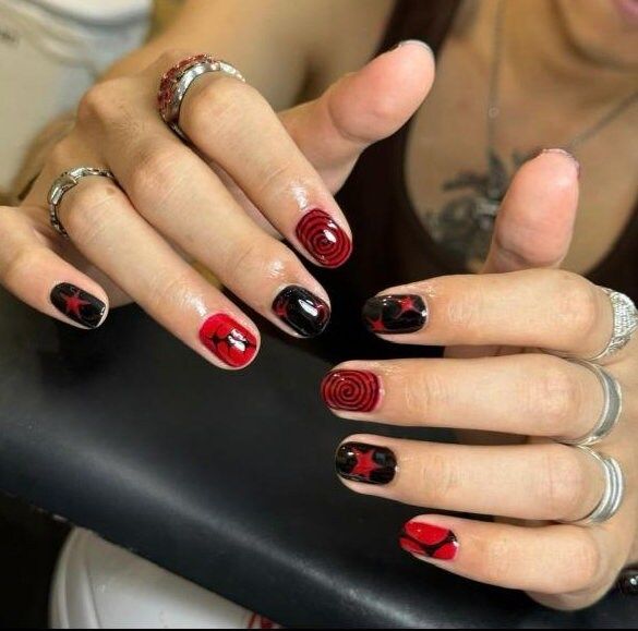 Edgy Red and Black Nail Design with Swirling Patterns and Star Motifs.