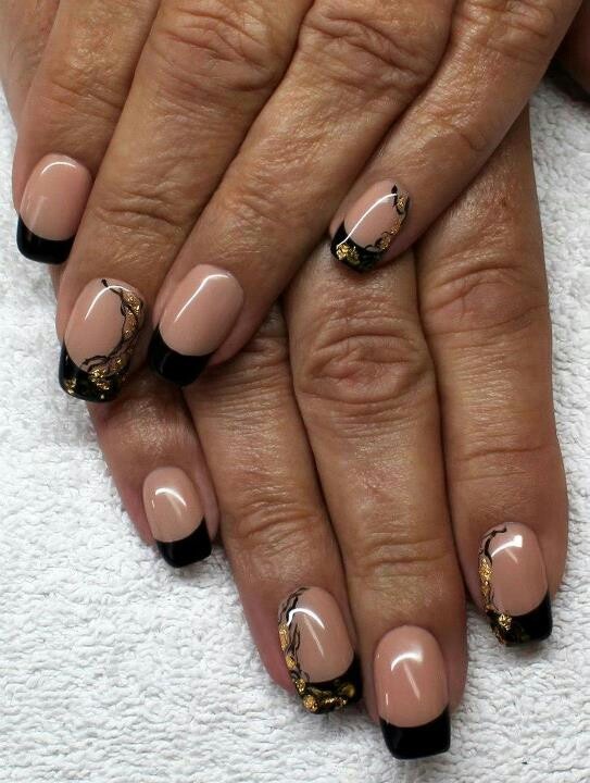 Sleek Nude and Black Nail Design with Elegant Golden Leaf Accents.