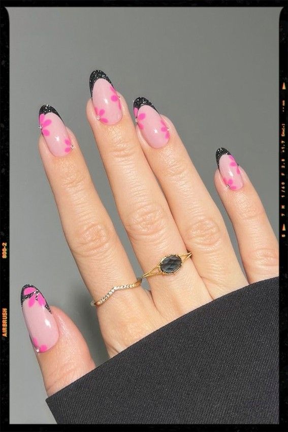 Chic Nail Design: Soft Pink Base with Floral Accents and Bold Black Tips.