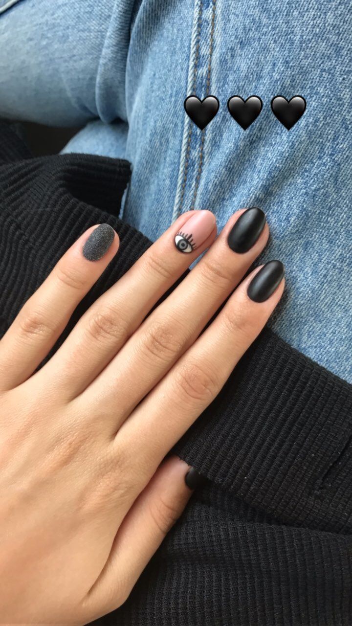 Chic Matte Black and Glitter Nail Design with Whimsical Eye Illustration.