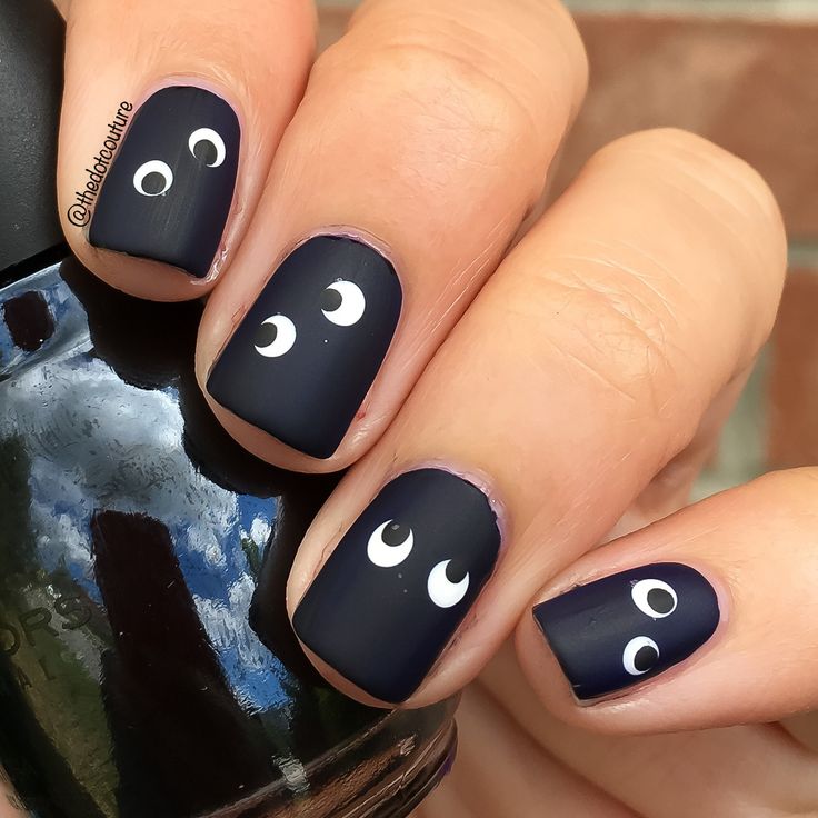 Whimsical Matte Black Nail Design with Eye Motifs for a Chic, Statement Look.