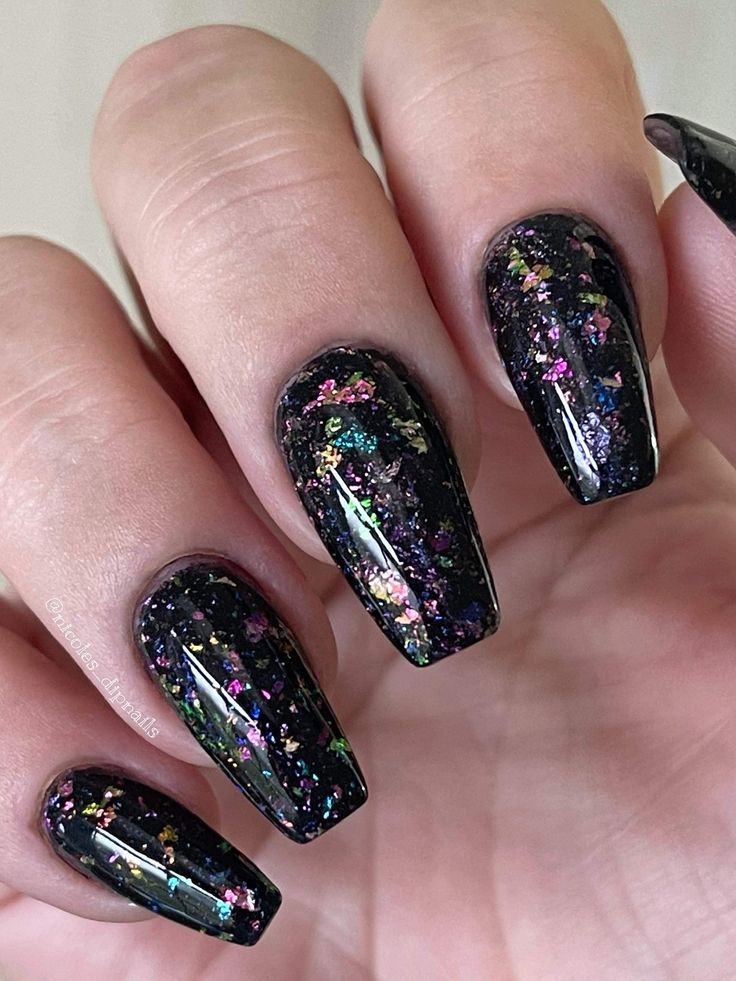 Glamorous Elongated Black Nail Design with Vibrant Glitter Flecks.