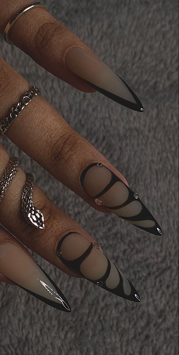 Elegant Stiletto Nail Design: Matte and Glossy Fusion with Intricate Patterns and Glamorous Rhinestones.