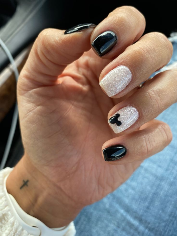 Chic Black and Glittering White Nail Design with Playful Detailing.