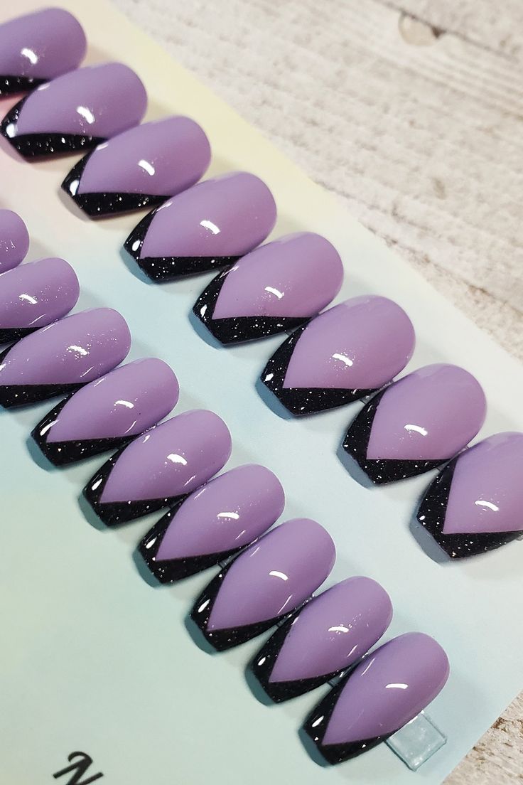 Chic Almond-Shaped Nail Design: Glossy Lavender with Sleek Black Accents and Glitter Highlights.