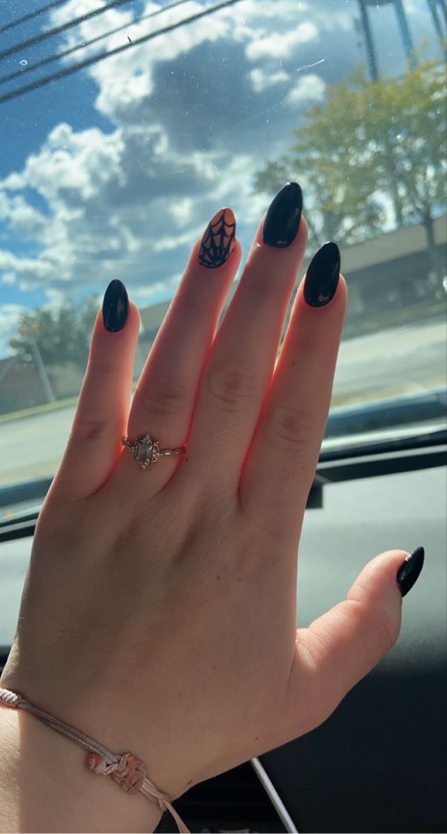 Elegant Black Almond-Shaped Manicure with Seasonal Spiderweb Design and Complementary Ring.