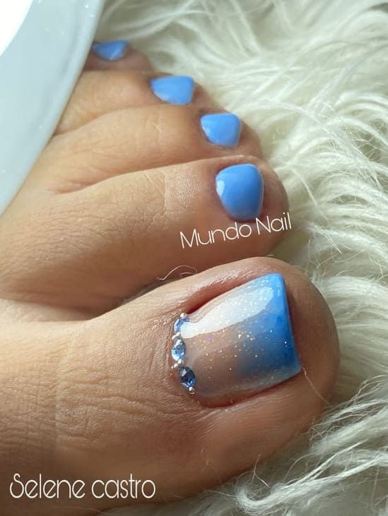 Elegant Blue Gradient Nail Design with Ombre and Rhinestones.