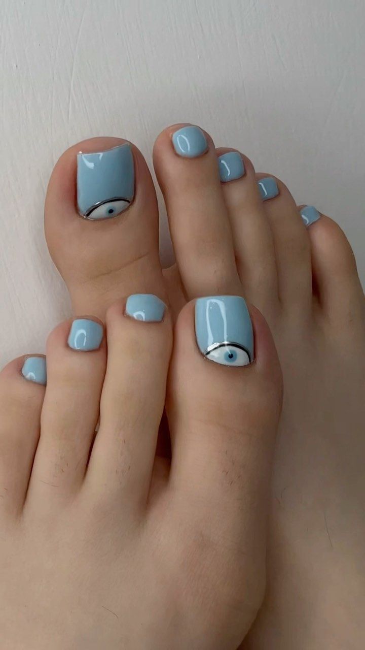 Trendy Light Blue Pedicure with Unique Eye Motifs and Sleek Lines.