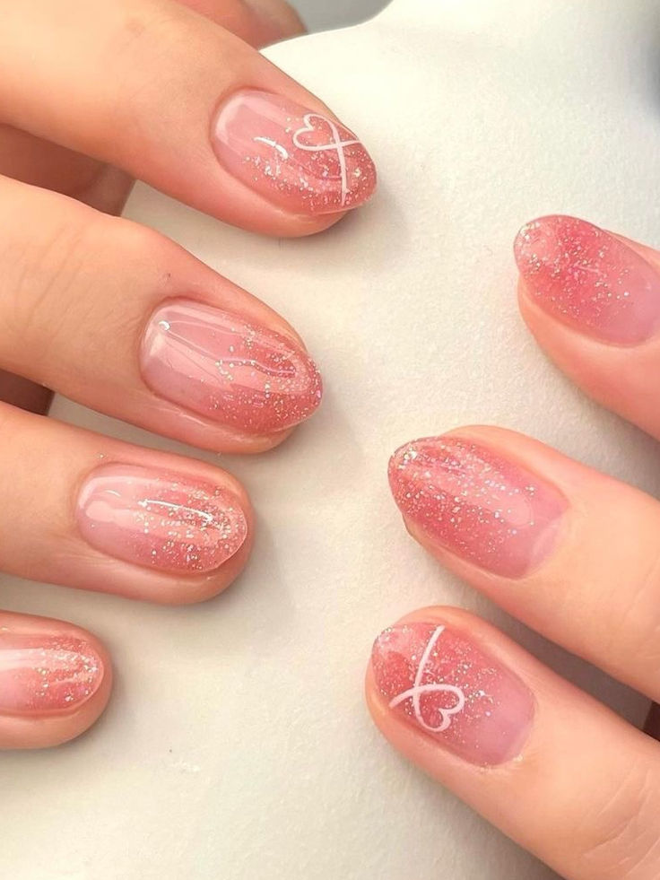 Romantic Pink Ombre Nails with Shimmer and Heart Accents for Elegant Occasions.