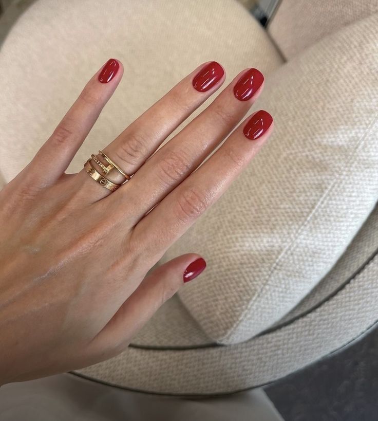 Elegant Red Nail Design with Sophisticated Gloss and Gold Rings.