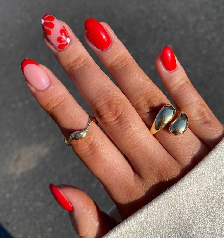 Chic Red and Pink Nail Design with Floral Accents and Gold Rings.