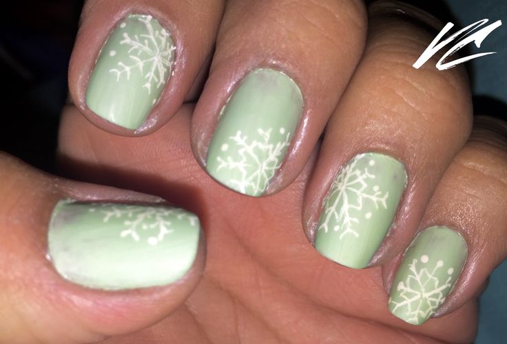 Festive Frosty Green Nail Design with Whimsical White Snowflakes for the Holiday Season.