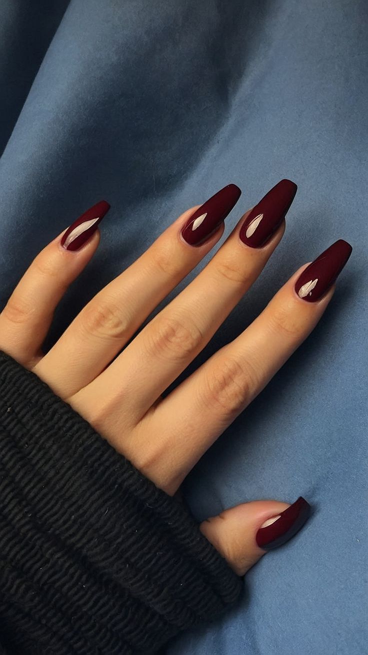 Sophisticated Deep Burgundy Almond-Shaped Nails with Glossy Finish and Intriguing Accents.