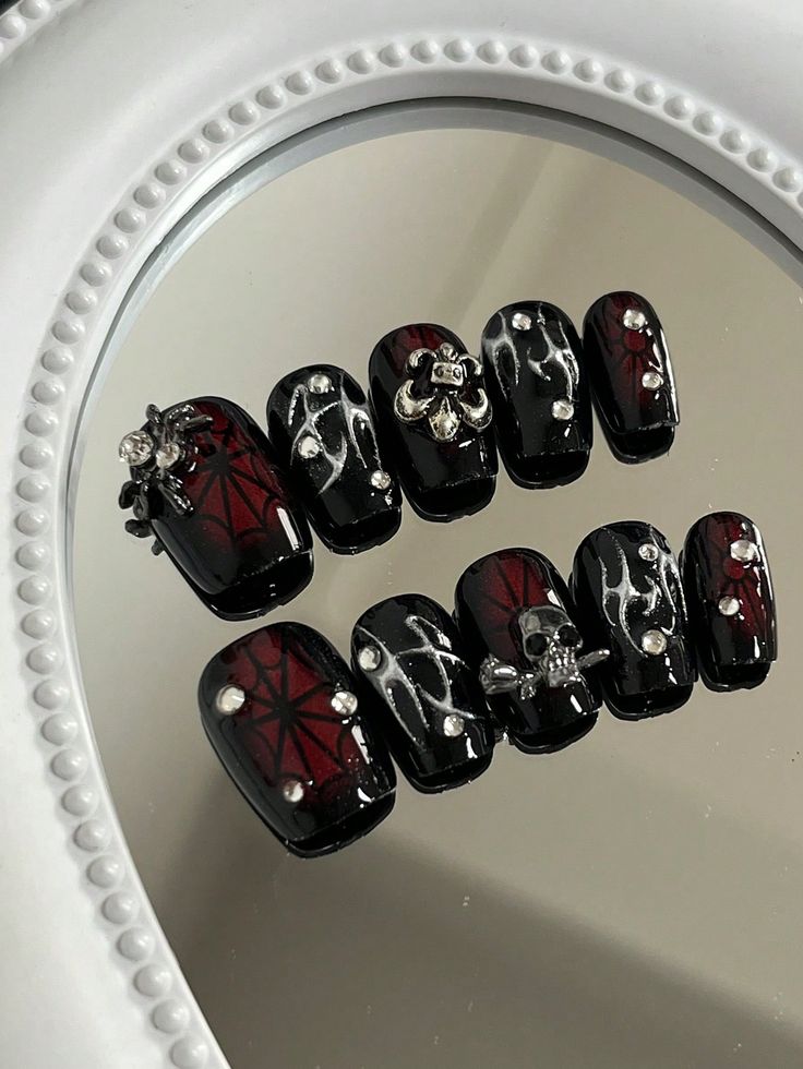 Dramatic Gothic Nail Design: Black Base with Bold Red, Spider Web Patterns, and Metallic Accents.