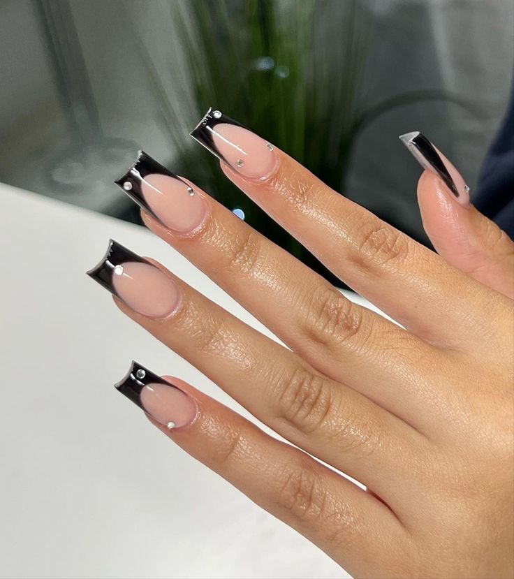 Chic Nail Design: Contemporary French Tips with Black Accents and Glamorous Gems.