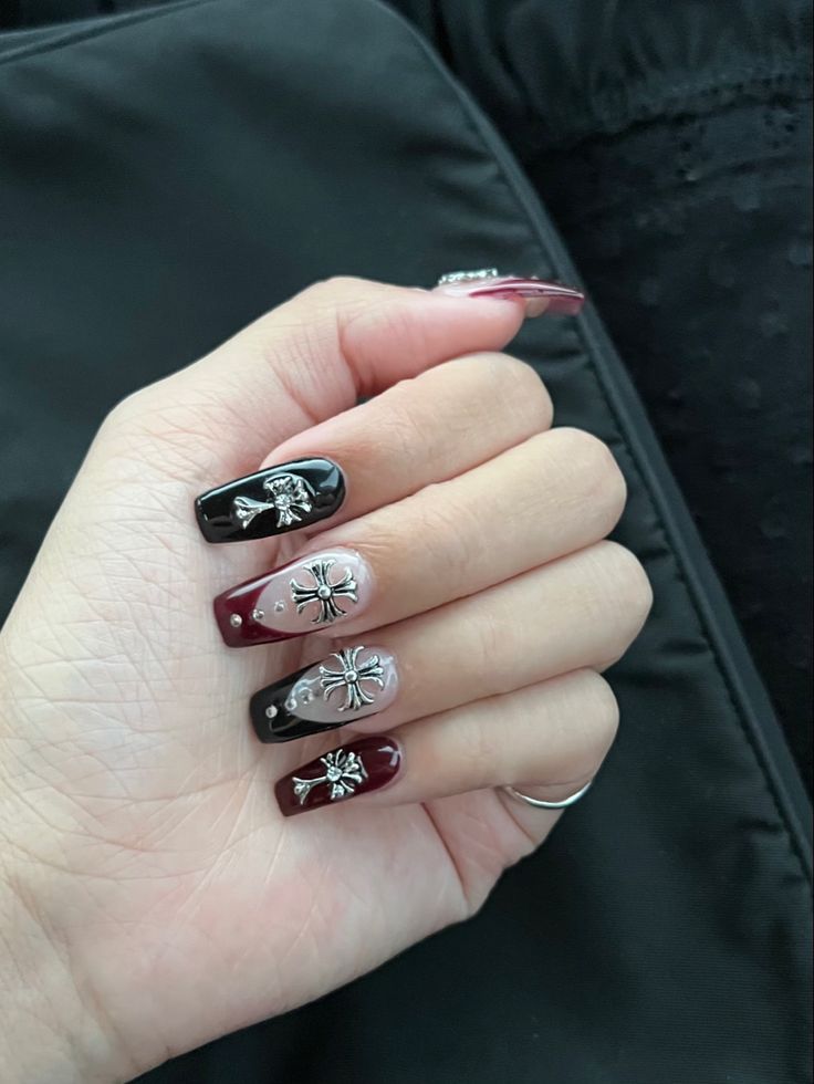 Sophisticated Nail Art: Deep Burgundy and Glossy Black Design with Intricate Silver Embellishments.