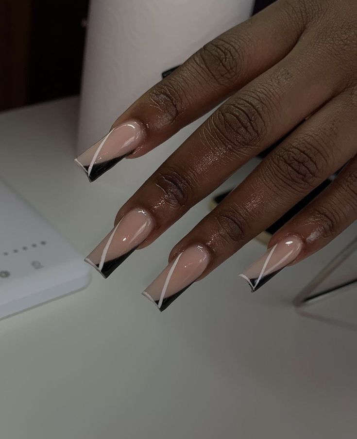 Elegant Edgy Nail Design: Soft Nude and Bold Black with Sharp French Tips and Delicate White Accents.