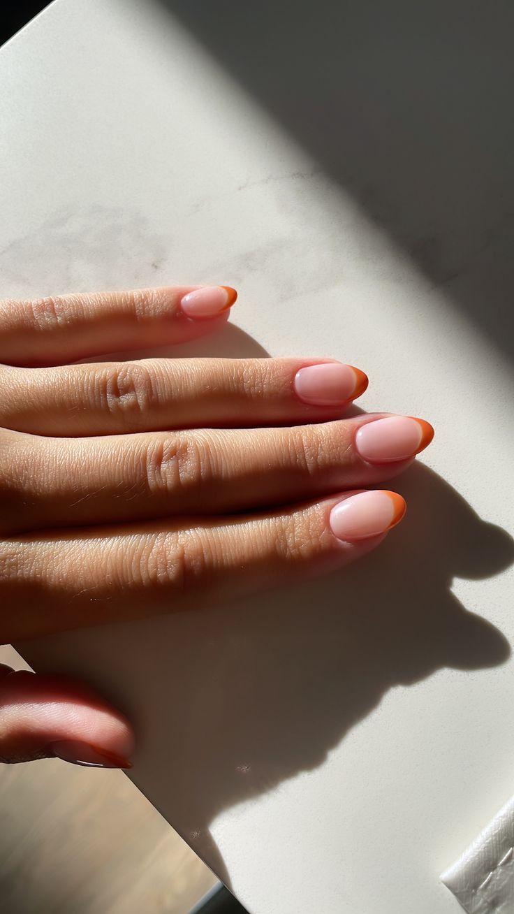 Chic Almond-Shaped Nails: Elegant Soft Pink Base with Striking Orange Tips.