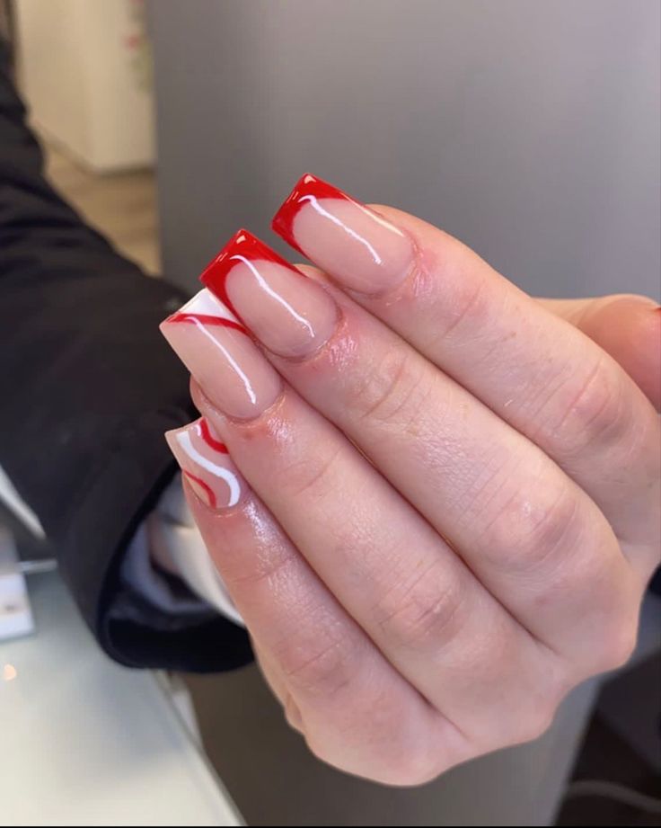 Chic Nail Design: Bold Red Tips and Swirling White Accents Blend Modern and Classic Styles.