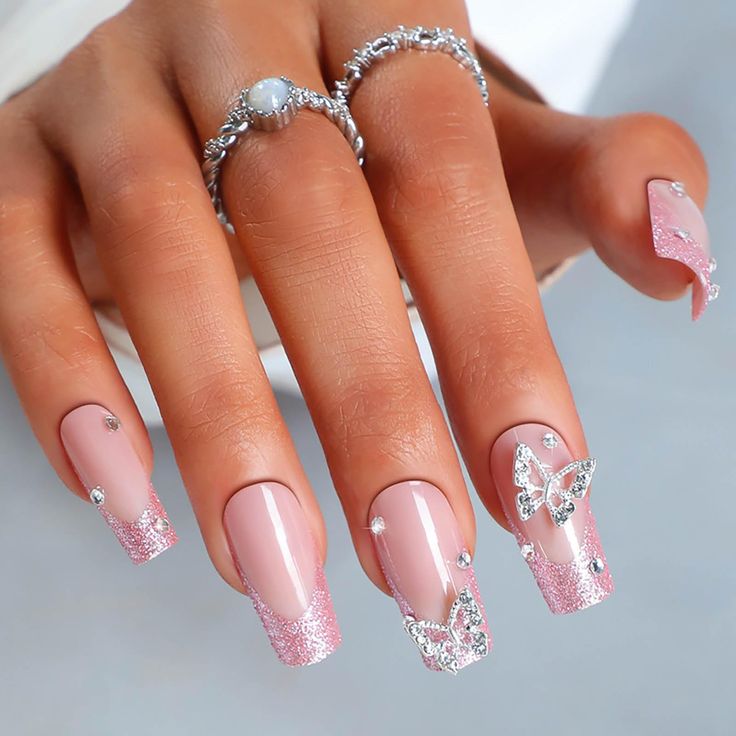 Elegant Soft Pink Nail Design with Glittery Tips and Whimsical Butterfly Accents.