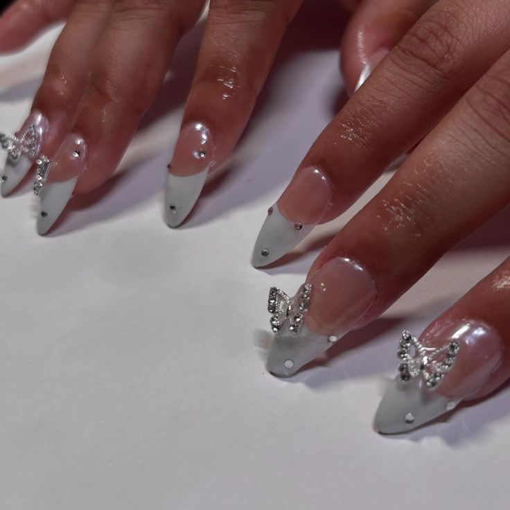 Chic French Tip Nail Design with Rhinestones and Butterfly Accents.