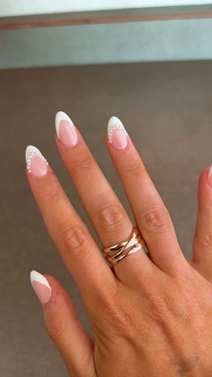 Chic French Manicure with Soft Pink and White Tips, Enhanced by Beaded Embellishments and Rose Gold Rings.