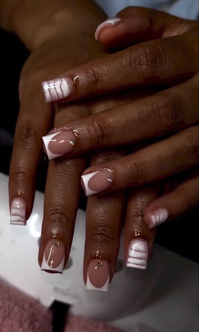 Sophisticated Nude and White Nail Design with Artistic Patterns and Sparkling Accents.